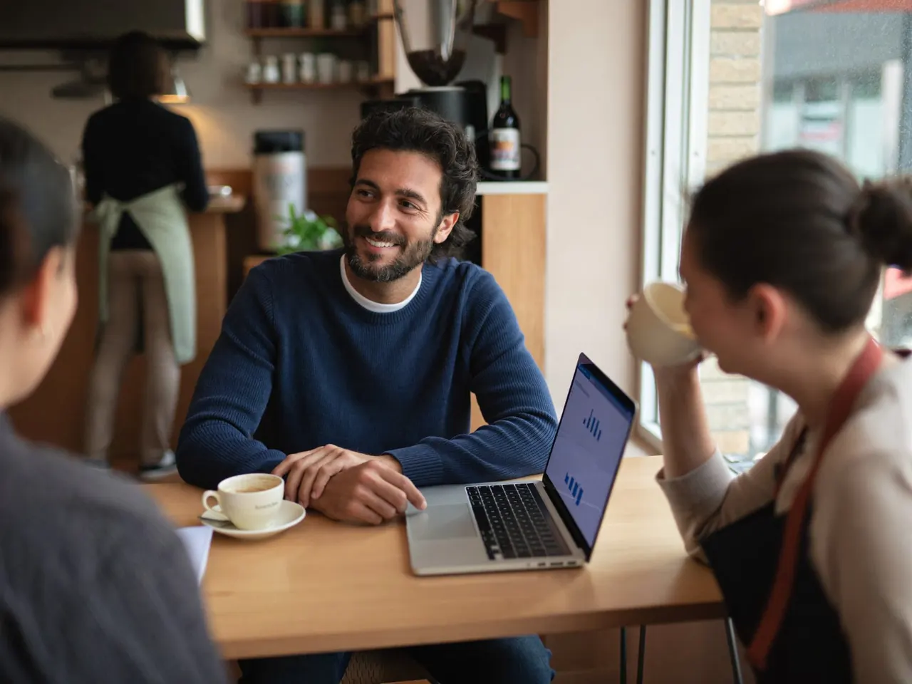 Marketing consultant reviewing results on a laptop with a coffee shop owner